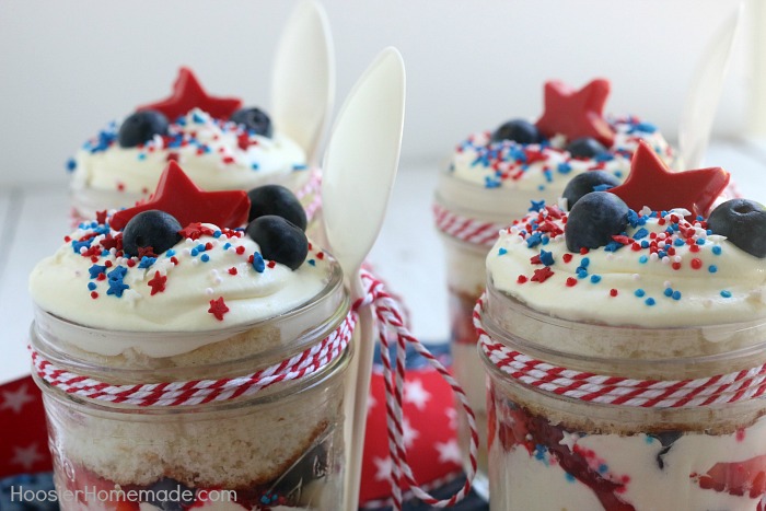 Layers of cake, pudding, whipped topping, strawberries, blueberries and more