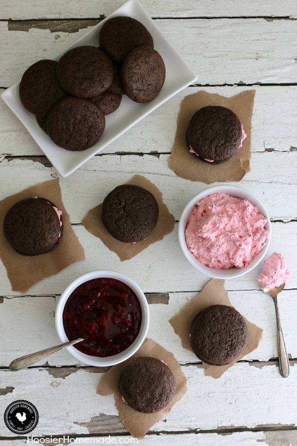 Raspberry Whoopie Pies - fluffy raspberry filling sandwiched between 2 chocolate cookies! Be sure to save room! You won't want to miss this one! Pin to your Recipe Board!