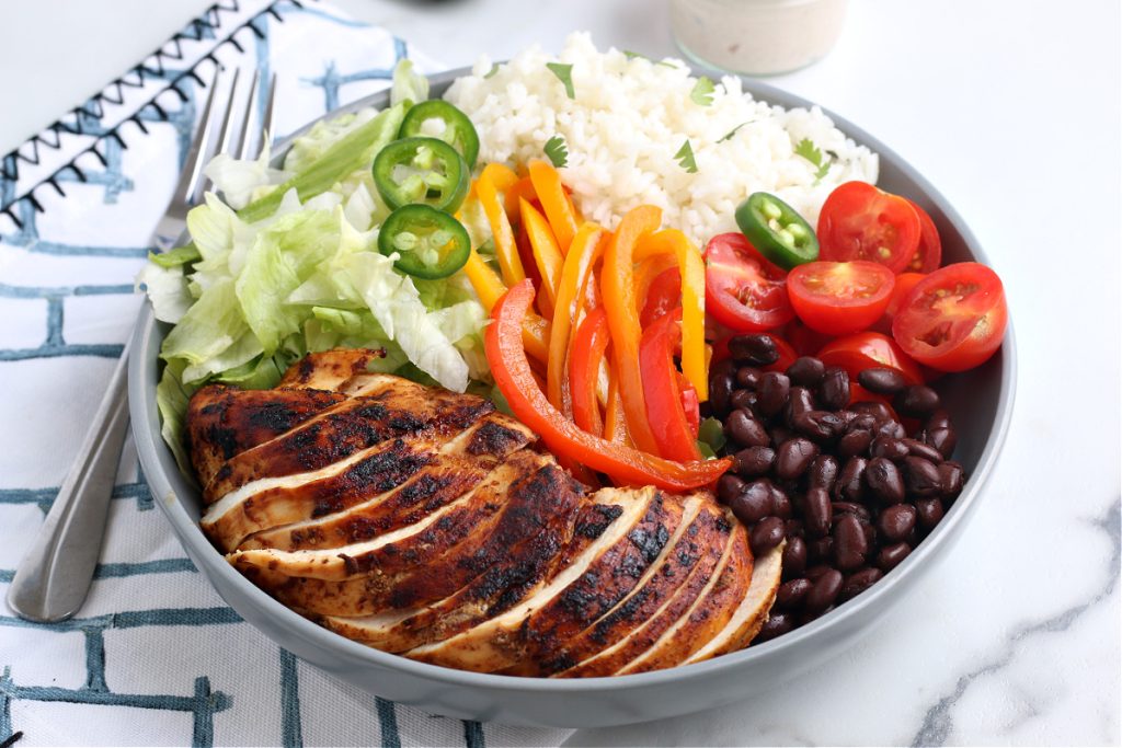burrito bowl recipe in gray bowl with fork and blue stripe napkin