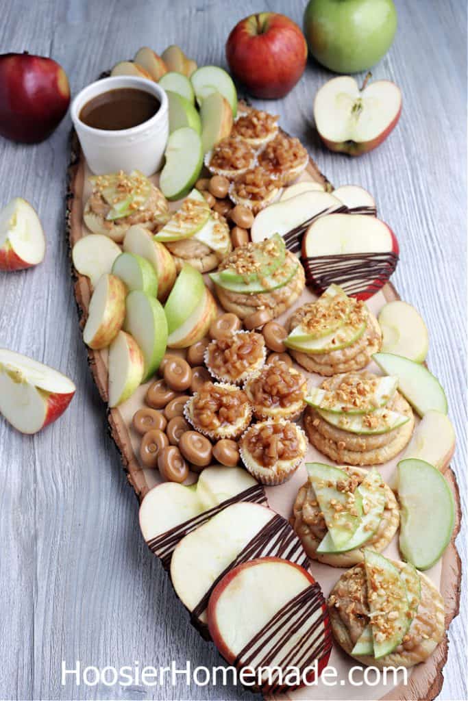 caramel apple treats on a board including homemade caramel sauce, cookies and candy