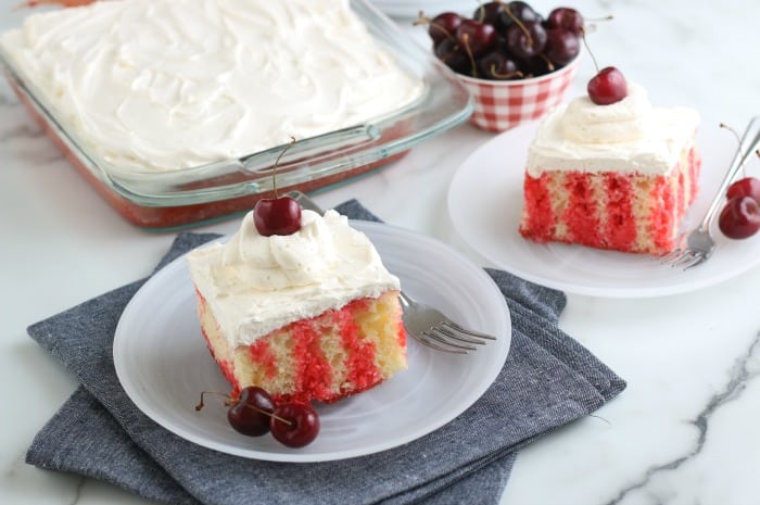 Cherry topped cakes on white plates.