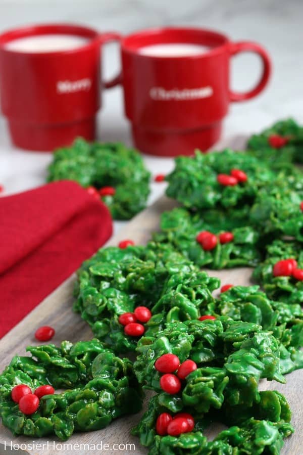wreath cookies on board with mugs of milk 