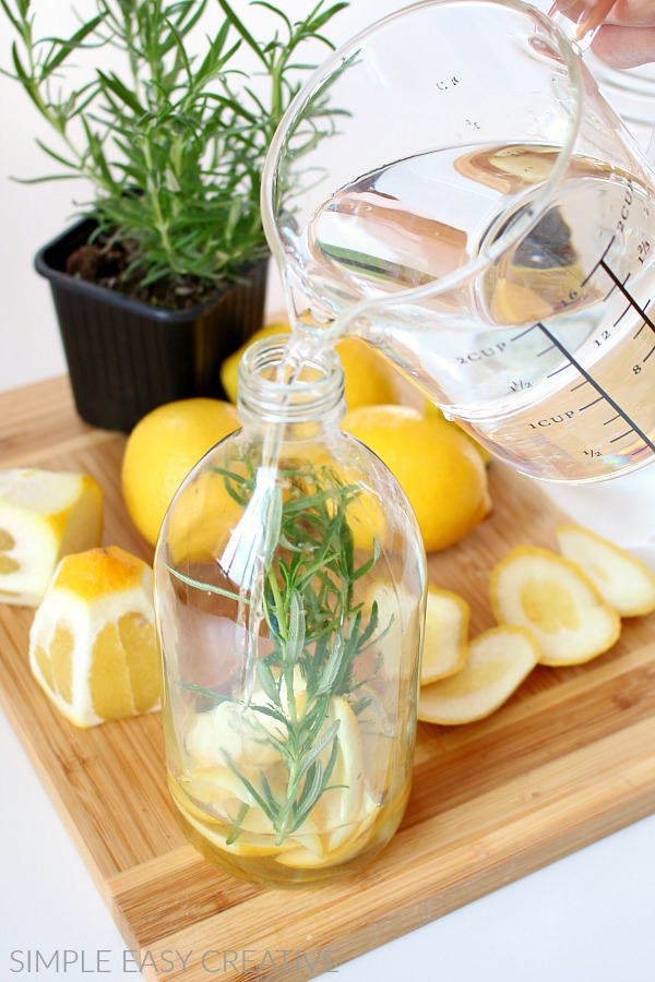 Pour vinegar, water and essential oil cleaning solution into glass bottle. 