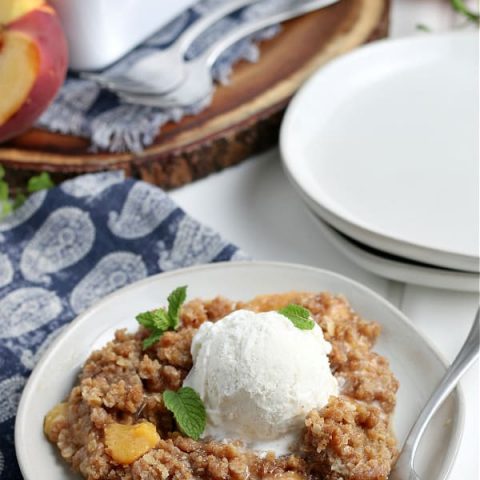 Peach Crisp served on white plate with vanilla ice cream