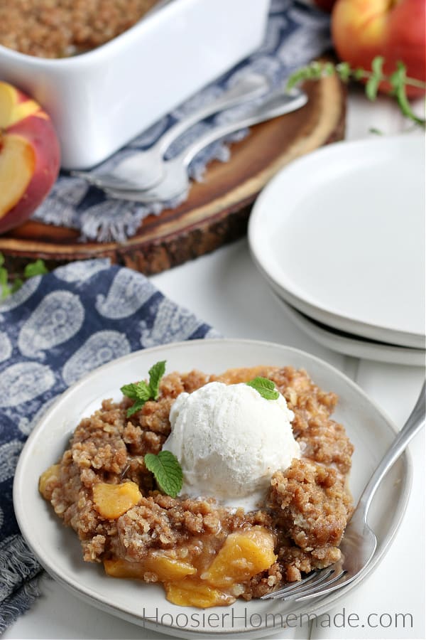 Peach Crisp served on white plate with vanilla ice cream 