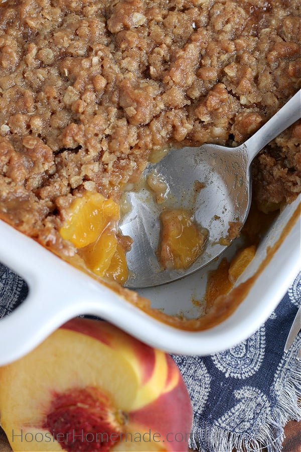Peach Crisp in white baking dish with serving spoon 