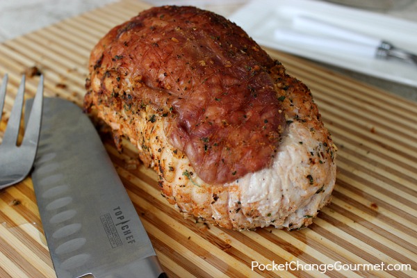 a roasted turkey breast on a chopping board with a fork and knife on the side