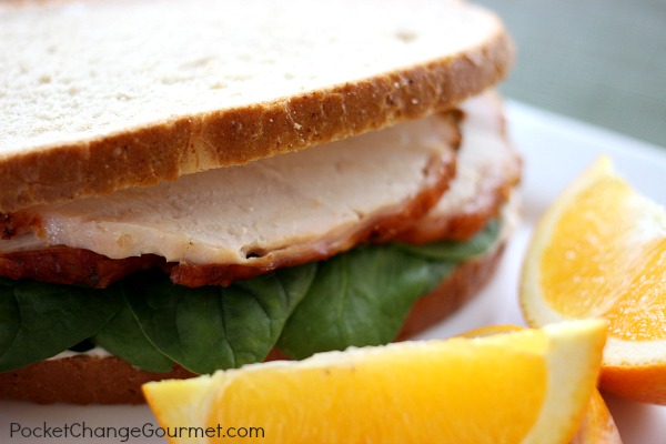 a sliced turkey breast sandwiched with a bread and oranges on the side