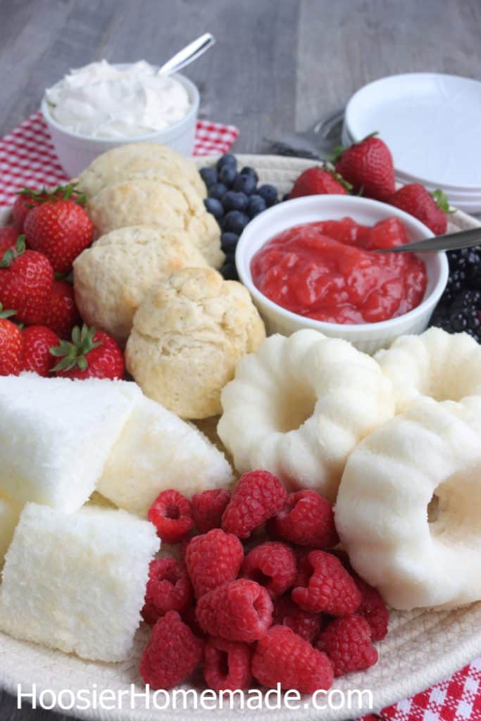 Strawberry shortcake dessert board with biscuits, angel food cake, fresh berries and strawberry topping for an easy spring dessert